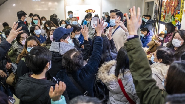A store assistant speaks into a megaphone as people raise their hands while waiting in line to purchase protective masks at a shopping mall in Hong Kong on Jan. 29. Photographer: Justin Chin/Bloomberg