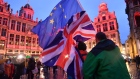 Pedestrians wave EU and U.K. flags in Brussels on Thursday, Jan. 30, 2020