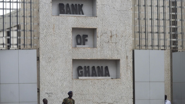 A soldier and policemen stand guard outside the headquarters of Ghana's central bank, also known as the Bank of Ghana, in Accra. Photographer: Ty Wright/Bloomberg