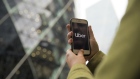 A commuter uses the Uber Technologies Inc. app on a smartphone in view of 30 St Mary Axe also known as 'the Gherkin' in this arranged photograph in London, U.K., on Monday, Nov. 25, 2019. Uber lost its license in London for the second time in less than three years, putting one of its biggest markets outside of the U.S. at risk after the transport regulator said it failed to address safety concerns. Photographer: Jason Alden/Bloomberg