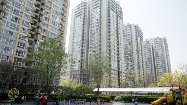 People stand in a playground in front of residential buildings in the Shuangjing area of Beijing, China, on Monday, April 16, 2018. New home prices in Beijing and Shanghai have jump more than 25 percent over the last two years. Photographer: Giulia Marchi/Bloomberg
