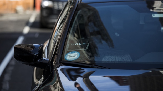 The Uber Technologies Inc. logo is seen on the windshield of a vehicle in New York, U.S., on Thursday, Aug. 9, 2018. New York's city council dealt a political blow to Uber Technologies Inc. and other app-based car-for-hire companies by approving a one-year industry wide cap on new licenses and giving the city Taxi & Limousine Commission authority to set minimum pay standards for drivers. Photographer: John Taggart/Bloomberg