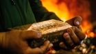 A worker carries a 28 kilogram gold bar after casting and cleaning in the foundry at the South Deep gold mine, operated by Gold Fields Ltd., in Westonaria, South Africa. Photographer: Waldo Swiegers/Bloomberg