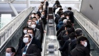 People wearing face masks ride escalators on February 13, 2020 in Tokyo, Japan.  