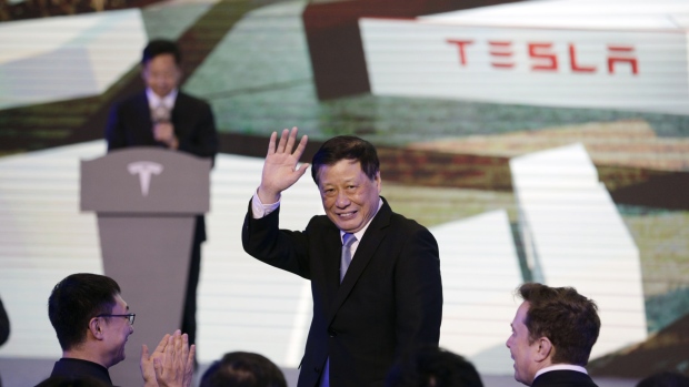 Ying Yong waves as Elon Musk watches, during the Tesla China-Made Model 3 delivery ceremony 