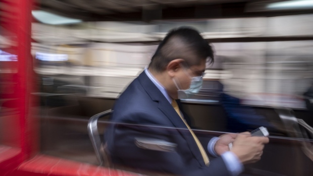 A passenger wearing a protective mask rides a tram in Hong Kong, China, on Wednesday, Feb. 12, 2020. Hong Kong's exchange faces a challenging year as the spreading coronavirus chokes off deals, adding more urgency to its efforts to convince Beijing to further open its markets and cement the bourse's role as a gateway to China's corporate giants. Photographer: Justin Chin/Bloomberg