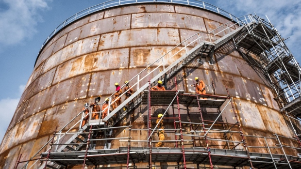 Workers climb scaffolding surrounding a storage tank at the under-construction Dangote Industries Ltd. oil refinery and fertilizer plant site in the Ibeju Lekki district, outside of Lagos, Nigeria, on Thursday, July 5, 2018. The $10 billion refinery, set to be one of the world’s largest and process 650,000 barrels of crude a day, should be near full capacity by mid-2020, Devakumar Edwin, group executive director at Dangote Industries said in an interview. Photographer: Tom Saater/Bloomberg