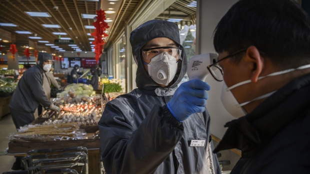 A Chinese worker checks the temperature of a customer as he wears a protective suit and mask at a supermarket in Beijing on Feb. 11, 2020.