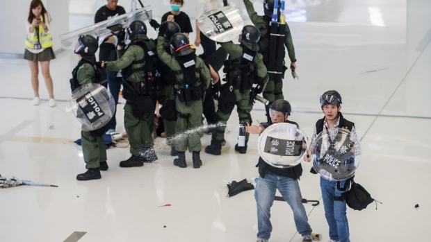Riot police deploy pepper spray inside the New Town Plaza shopping mall, operated by Sun Hung Kai Properties Ltd., during a protest in the Shatin district of Hong Kong, China, on Sunday, July 14, 2019. Hong Kong police arrested more than 40 people after attempts to clear the remnants of a mass anti-government march resulted in dramatic clashes with demonstrators inside a suburban shopping mall, piling more pressure on embattled leader Carrie Lam. Photographer: Paul Yeung/Bloomberg