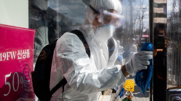 A worker wearing a protective suit wipes disinfectant on the door of a clothing store on Munjeong-dong Rodeo Street in the Songpa district of Seoul, South Korea, on Thursday, Feb. 27, 2020. More coronavirus cases were reported in other countries than in China for the first time, the World Health Organization said, a significant development highlighting the spread of the epidemic around the globe. The U.S. urged travelers to reconsider trips to South Korea as the country’s number of cases rose to more than 1,500. Photographer: SeongJoon Cho/Bloomberg