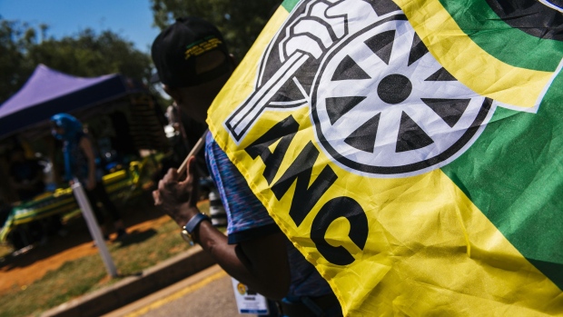 A pedestrian carries an ANC flag during the 54th national conference of the African National Congress party in Johannesburg, South Africa, on Sunday, Dec. 17, 2017. The leadership conference of South Africa’s ruling African National Congress party has accepted the credentials of the delegates, opening the way for the start of voting to choose the party’s top officials, according to five people familiar with the deliberations. Photographer: Waldo Swiegers/Bloomberg