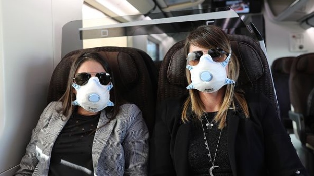 MILAN, ITALY - FEBRUARY 25: Two passengers wear protective masks as they travel on a train from Rome to Milan on February 25, 2020 in Milan, Italy. The country is struggling to understand how it went from six coronavirus cases to 374 cases and 12 dead since last Friday, becoming Europe's worst-affected country. Many communities across the Lombardy and Veneto regions have seen the suspension of public events and church services, and the closure of grade schools, universities and museums. Twelve towns have been locked down entirely, with road blocks preventing the exit and entrance of people. The government has also imposed quarantines for those who have had close contact with confirmed cases of the illness. (Photo by Marco Di Lauro/Getty Images)