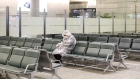 A man wearing a protective mask and raincoat sits in the arrivals area at Hongqiao International Airport in Shanghai, China on Sunday, Feb. 9, 2020. Photographer: Qilai Shen/Bloomberg