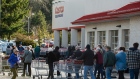 Shoppers wait in line to enter a Costco Wholesale Corp.
