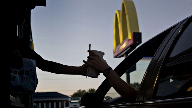 An employee hands a beverage to a customer at the drive-thru window of a McDonald's Corp. restaurant in Peru, Illinois. Photographer: Daniel Acker/Bloomberg