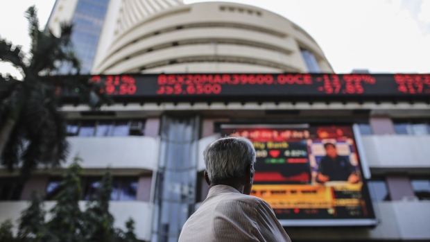 A person looks at a screen and electronic ticker board show outside the Bombay Stock Exchange (BSE) building in Mumbai, India, on Monday, March 9, 2020. A top Indian official said there's no need for the government to take immediate steps to support the economy following a crash in oil prices that has sent financial markets into a tailspin. Photographer: Dhiraj Singh/Bloomberg