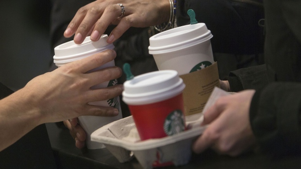 A barista hands a customer a drink inside a Starbucks coffee shop in New York. Photographer: Victor J. Blue/Bloomberg