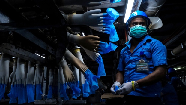 An employee monitors latex gloves on hand-shaped molds moving along an automated production line at a Top Glove Corp. factory in Setia Alam, Selangor, Malaysia, on Feb. 18, 2020. Photographer: Samsul Said/Bloomberg