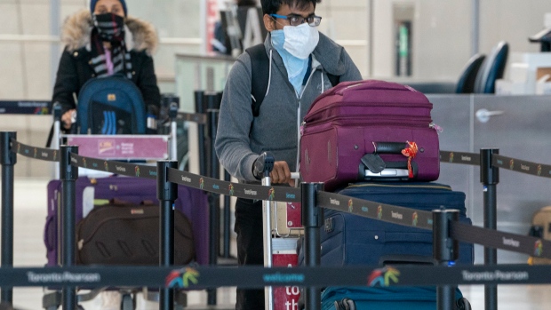Passengers wear masks as they arrive for their flight at Pearson Airport in Toronto on Friday, March