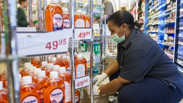 A worker wearing a protective face mask stocks products at store in Pretoria, South Africa. Photographer: Waldo Swiegers/Bloomberg