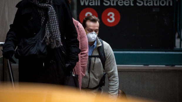 A pedestrian wearing a protective mask exits a Wall Street subway station near the New York Stock Exchange (NYSE) in New York, U.S., on Thursday, March 12, 2020. The rout in global stocks deepened as investors showed a lack of faith in the U.S. and European policy responses to the worsening spread of the coronavirus. The dollar surged. Photographer: Michael Nagle/Bloomberg