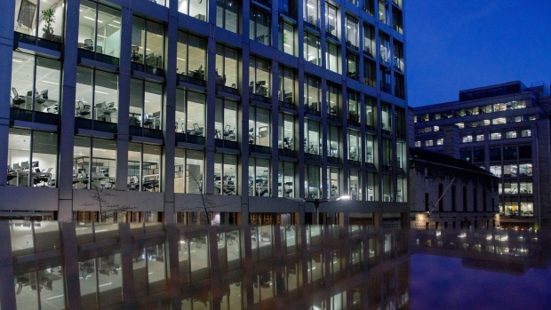 Office workers work at their illuminated desks at dusk in the City of London. Photographer: Luke MacGregor/Bloomberg