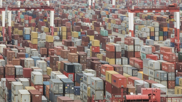 Shipping containers sit stacked next to gantry cranes at the Yangshan Deep Water Port in Shanghai, China, on Tuesday, Feb. 4, 2020. Chinese officials are hoping the U.S. will agree to some flexibility on pledges in their phase-one trade deal, people familiar with the situation said, as Beijing tries to contain a health crisis that threatens to slow domestic growth with repercussions around the world. Photographer: Qilai Shen/Bloomberg