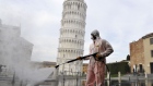  worker carries out sanitation operations for the Coronavirus emergency in Piazza dei Miracoli near to the Tower of Pisa in a deserted town on March 17, 2020 in Pisa, Italy. 