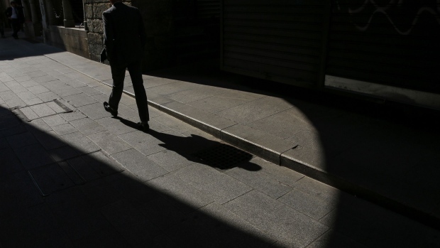 A pedestrian casts a shadow as he walks in central Milan, Italy, on Monday, Sept. 25, 2017. The Italian government sees the country's debt load starting to fall this year as the economy heads into a three-year stretch of 1.5 percent annual growth. Photographer: Stefan Wermuth/Bloomberg