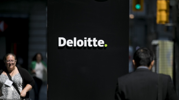 Pedestrians pass in front of Deloitte signage in Toronto. 