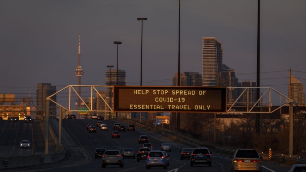 A digital sign telling motorists to limit travel during the coronavirus outbreak, is seen on a highway sign in Toronto, Ontario, Canada, on Saturday, March 21, 2020. The U.S. and Canada are poised to allow all those with work visas to continue to cross the border as the two countries hammer out details on new travel restrictions. Photographer: Cole Burston/Bloomberg