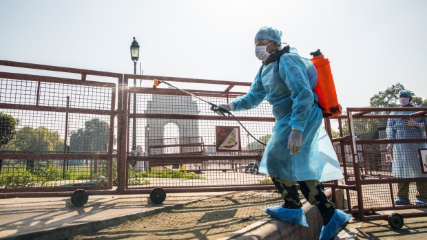 A security person sprays disinfectant near the India Gate monument in New Delhi on March 22. Photographer: Prashanth Vishwanathan/Bloomberg