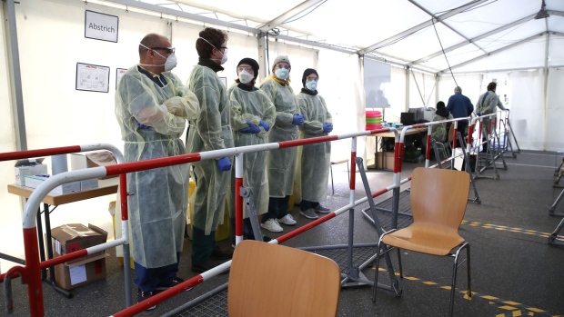 Medical personnel wait to take nose and throat mucous samples for coronavirus testing at a new outdoor facility at the Department of Infectious and Tropical Medicine at LMU Universtiy Hospital in Munich, on March 23. Photographer: Alexander Hassenstein/Getty Images