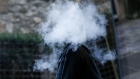 A pedestrian stands in a cloud of vapour after exhaling from an e-cigarette. Photographer: Hollie Adams/Bloomberg