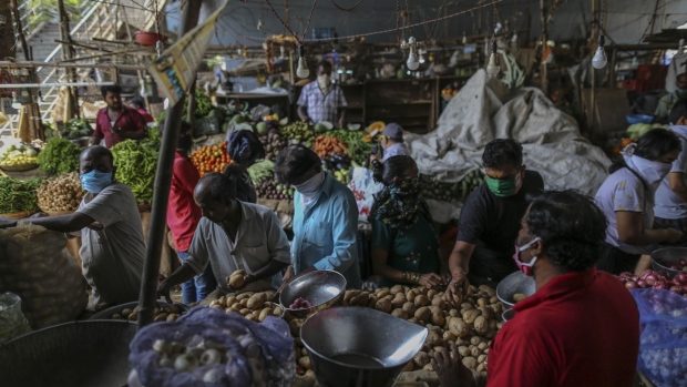 Customers wearing protective face masks buy vegetables at a market in Mumbai on Wednesday. Photographer: Dhiraj Singh/Bloomberg