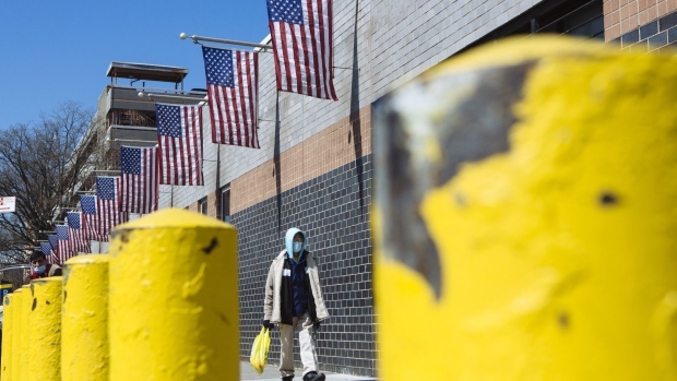 A person wearing a protective mask walks outside the Elmhurst Hospital Center in the Queens borough of New York, U.S., on Thursday, March 26, 2020. New York City is the epicenter of the coronavirus pandemic in the United States, putting historic pressure on a world-renowned healthcare system as the number of confirmed cases in the area grows exponentially. Photographer: Angus Mordant/Bloomberg
