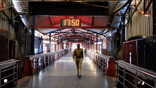 A police officer wearing a protective mask walk along an overpass inside the empty Delhi Junction railway station during a lockdown imposed due to the coronavirus in Delhi, India, on Monday, March 30, 2020. Indian Railways, the world’s fourth-biggest network, is converting at least 5,000 coaches into isolation wards amid fears the world’s most populous country after China may not have adequate infrastructure to deal with the pandemic. Photographer: T. Narayan/Bloomberg