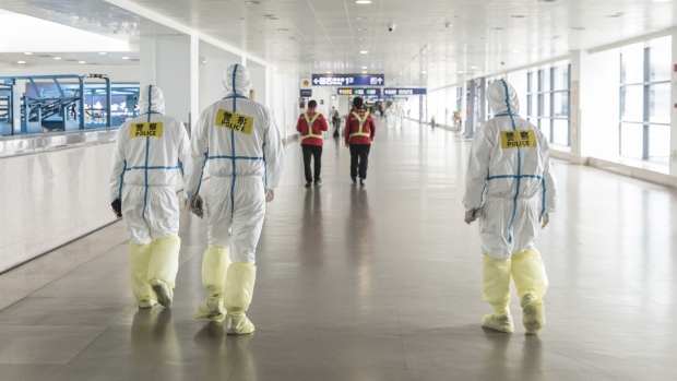 Airport employees wear full body protective suits at Pudong International Airport in Shanghai on March 28. Photographer: Qilai Shen/Bloomberg