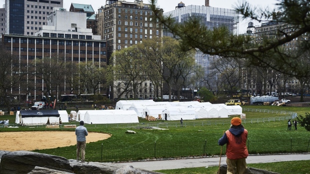 Pedestrians look at an emergency field hospital under construction in Central Park in New York, on March 30. Photographer: Gabby Jones/Bloomberg