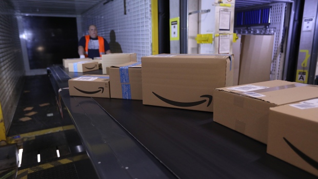 The Amazon.com Inc. logo sits on boxes moving along a conveyor into a truck dock ahead of shipping from an Amazon.com Inc. fulfilment center during the online retailer's Prime Day sales promotion day in Koblenz, Germany, on Monday, July 15, 2019. Amazon is tapping high-profile actors, athletes and social-media sensations like never before to maintain buzz around its Prime Day summer sale, now in its fifth year and battling increasing competition from rivals. Photographer: Krisztian Bocsi/Bloomberg