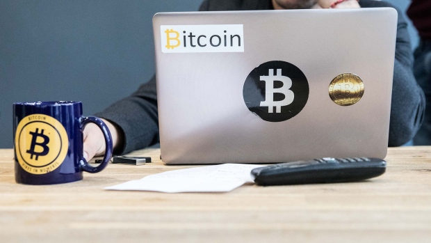 An employee uses a laptop computer branded with bitcoin logos inside the offices of La Maison du Bitcoin bank in Paris, France. Photographer: Chritophe morin/Bloomberg