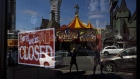 A closed sign hangs inside of a store in the Clifton Hill area in Niagara Falls