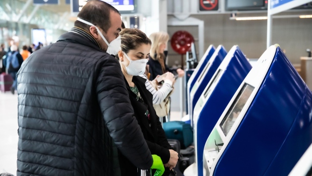 Travelers wear face masks while using Air France-KLM self-service check-in machines at Charles de Gaulle Airport, operated by Aeroports de Paris, in Roissy, France, on Thursday, March 12, 2020. President Donald Trump’s 30-day ban on Europeans traveling to the U.S. delivers a hammer blow to a global airline industry that was already at risk of losing as much as $113 billion in passenger revenue this year because of the coronavirus. Photographer: Christophe Morin/Bloomberg