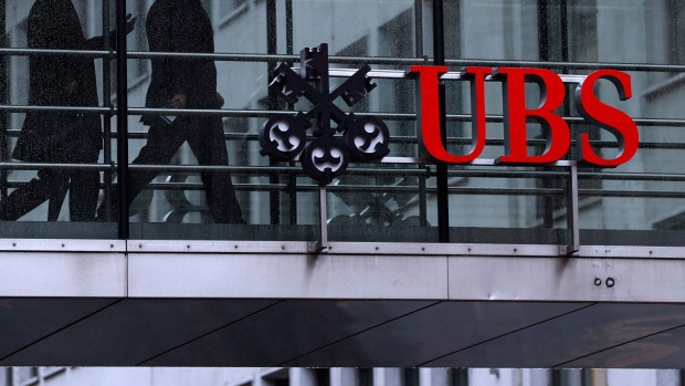 Employees pass between offices as UBS Group AG logo sits on a walkway at the UBS headquarters in Zurich, Switzerland, on Monday, Jan. 22, 2018. A UBS loan backed by shares of Steinhoff International Holdings NV was to blame for the majority of the Swiss banks 79 million francs ($82 million) in credit losses in the fourth quarter, a person with knowledge of the matter said. Photographer: Stefan Wermuth/Bloomberg