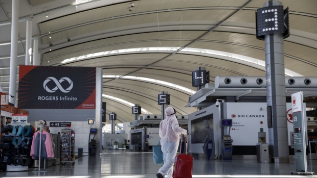 A traveler wearing a protective suit and mask walks through a terminal at Toronto Pearson International Airport on April 8. Photographer: Cole Burston/Bloomberg