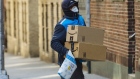 A worker wearing a protective mask and gloves carries Amazon.com Inc. boxes during a delivery in the Bronx borough of New York on March 26. Photographer: Angus Mordant/Bloomberg