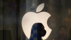 A employee wearing a protective mask is silhouetted while standing in front of an Apple Inc. logo at the company's store, temporarily closed due to the coronavirus, in the Ginza area of Tokyo, Japan, on Sunday, March 15, 2020. 