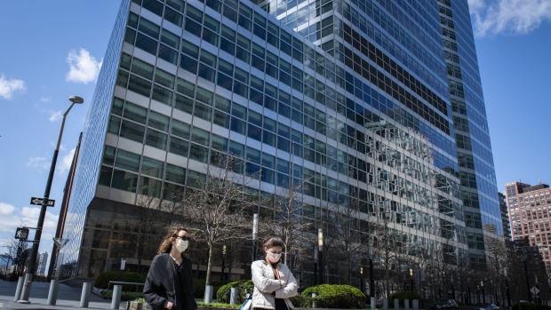 Pedestrians wearing protective masks walk past Goldman Sachs Group Inc. headquarters in New York, U.S., on Saturday, April 11, 2020.