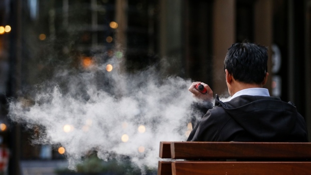 A pedestrian exhales a cloud of vapour from a vape device in London, U.K., on Thursday, Oct. 17, 2019. Vaping has helped tens of thousands of Britons quit smoking each year, a study showed, underlining the U.K.'s more tolerant stance on the alternative to cigarettes as a backlash grows in the U.S. Photographer: Hollie Adams/Bloomberg