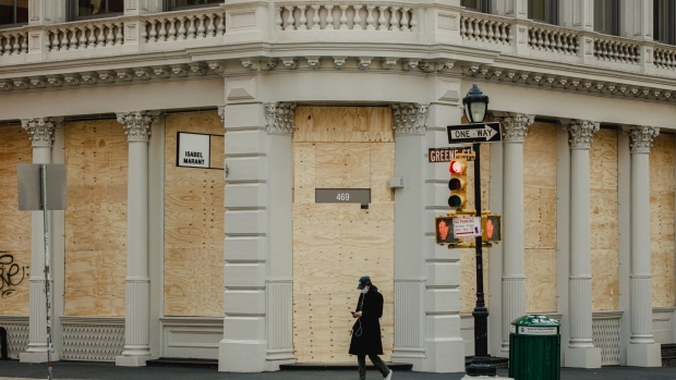 A pedestrian passes a boarded up store in the SoHo neighborhood of New York on April 11. Photographer: George Etheredge/Bloomberg